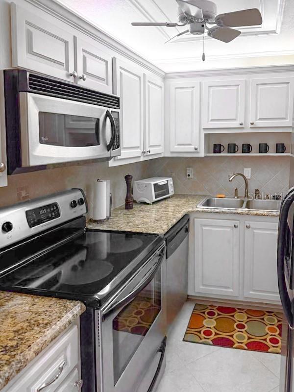 3043 S Atlantic Ave Unit 204, Daytona Beach, FL 32118 - kitchen with stainless steel appliances, a sink, white cabinetry, ceiling fan, and light tile patterned floors
