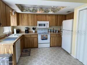 2898 Ocean Shore Blvd Unit 603, Ormond Beach, FL 32176 - kitchen with white appliances, light countertops, light floors, and brown cabinets