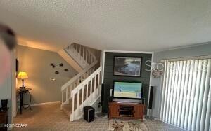 2898 Ocean Shore Blvd Unit 603, Ormond Beach, FL 32176 - living area with stairway, a textured ceiling, and carpet flooring