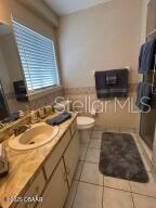 2898 Ocean Shore Blvd Unit 603, Ormond Beach, FL 32176 - full bathroom with vanity, tile patterned flooring, toilet, and a shower with shower door