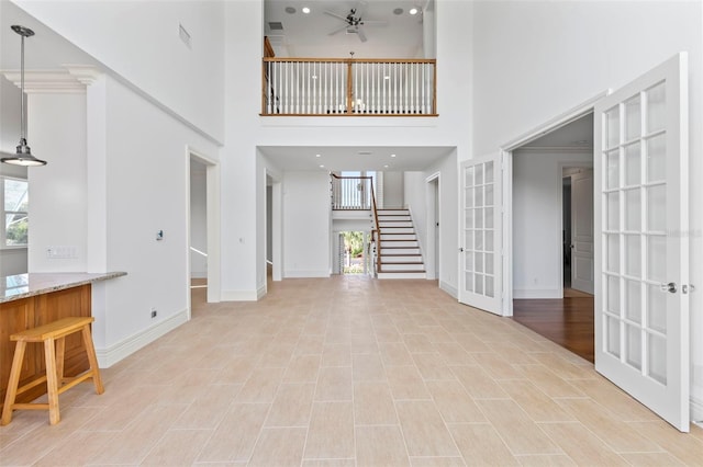 2275 Genesea Ln, Vero Beach, FL 32963 - unfurnished living room with healthy amount of natural light, a towering ceiling, stairway, baseboards, and ceiling fan