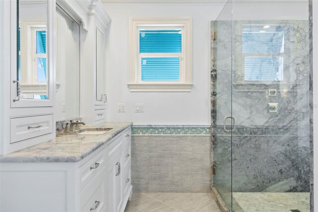 2275 Genesea Ln, Vero Beach, FL 32963 - bathroom with vanity, a marble finish shower, wainscoting, healthy amount of natural light, and tile patterned floors