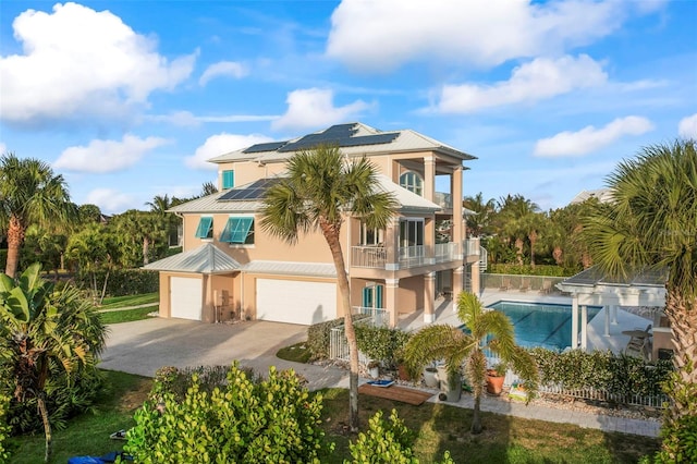 2275 Genesea Ln, Vero Beach, FL 32963 - back of property featuring a balcony, solar panels, metal roof, stucco siding, and an attached garage