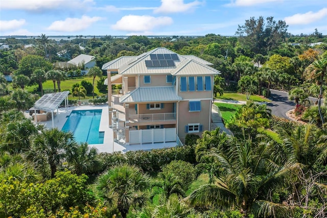 2275 Genesea Ln, Vero Beach, FL 32963 - rear view of property with a balcony, solar panels, an outdoor pool, metal roof, and a standing seam roof