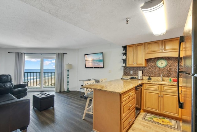 3647 S Atlantic Ave Unit 7C, Daytona Beach, FL 32118 - kitchen with open floor plan, a peninsula, wood finished floors, tasteful backsplash, and a textured ceiling