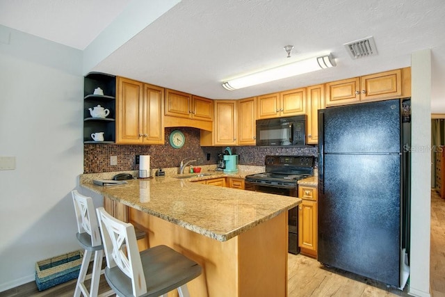 3647 S Atlantic Ave Unit 7C, Daytona Beach, FL 32118 - kitchen with black appliances, a sink, a peninsula, light wood-style floors, and tasteful backsplash