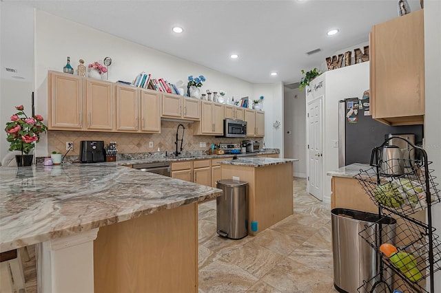 45 Saint Andrews Ct, Palm Coast, FL 32137 - kitchen featuring stainless steel appliances, a peninsula, light brown cabinetry, light stone counters, and decorative backsplash