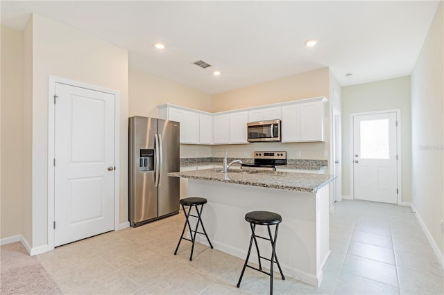 2241 Litchfield Loop, Deland, FL 32720 - kitchen with appliances with stainless steel finishes, a kitchen bar, light stone counters, white cabinets, and an island with sink