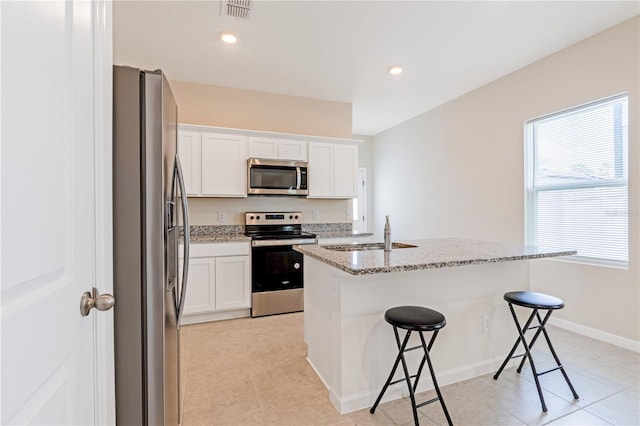 2241 Litchfield Loop, Deland, FL 32720 - kitchen featuring stainless steel appliances, a breakfast bar, light stone counters, white cabinetry, and an island with sink