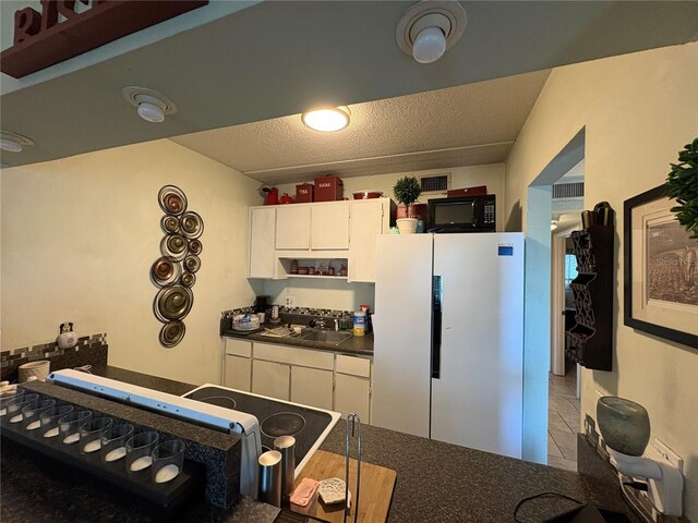 411 N Halifax Ave Unit 208, Daytona Beach, FL 32118 - kitchen featuring freestanding refrigerator, black microwave, dark countertops, white cabinets, and light tile patterned floors
