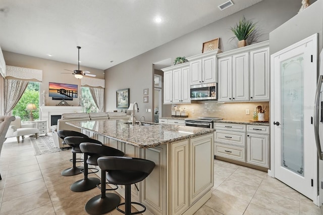33 Coquina Ridge Way, Ormond Beach, FL 32174 - kitchen with appliances with stainless steel finishes, a sink, open floor plan, a kitchen bar, and light stone counters