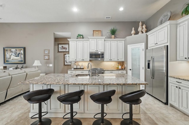 33 Coquina Ridge Way, Ormond Beach, FL 32174 - kitchen featuring stainless steel appliances, a sink, white cabinetry, light stone counters, and open floor plan