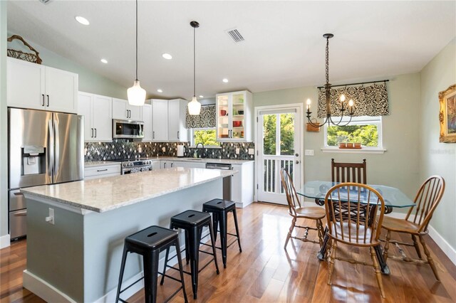 2250 Davis Dr, New Smyrna Beach, FL 32168 - kitchen featuring appliances with stainless steel finishes, a center island, wood finished floors, tasteful backsplash, and a breakfast bar