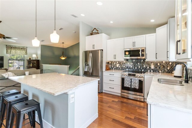 2250 Davis Dr, New Smyrna Beach, FL 32168 - kitchen featuring stainless steel appliances, vaulted ceiling, decorative backsplash, a kitchen breakfast bar, and a center island