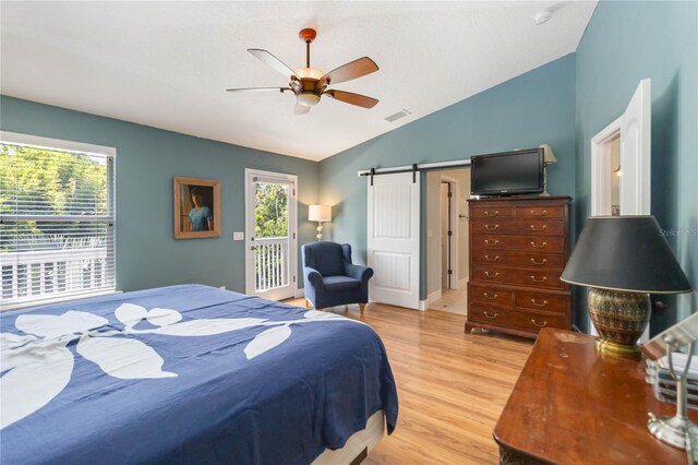 2250 Davis Dr, New Smyrna Beach, FL 32168 - bedroom with wood finished floors, vaulted ceiling, ceiling fan, access to outside, and a barn door