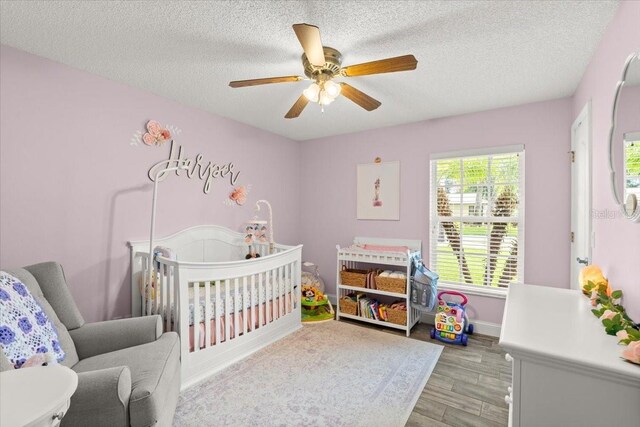3132 Mango Tree Dr, Edgewater, FL 32141 - bedroom featuring a crib, a textured ceiling, light wood-type flooring, and ceiling fan
