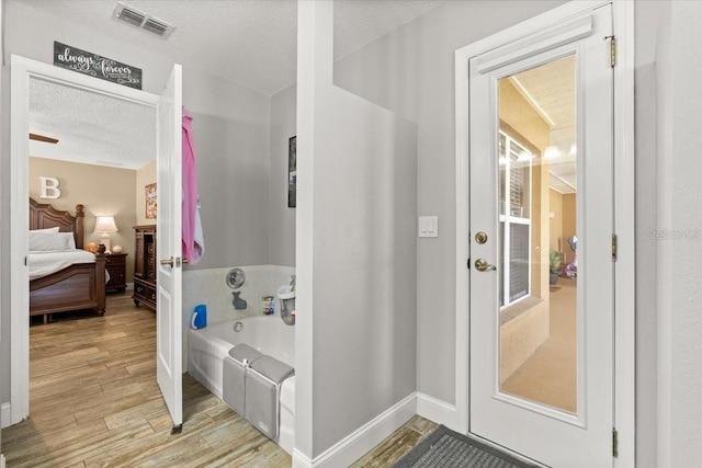 3132 Mango Tree Dr, Edgewater, FL 32141 - bathroom featuring wood finished floors, a garden tub, a textured ceiling, and ensuite bathroom