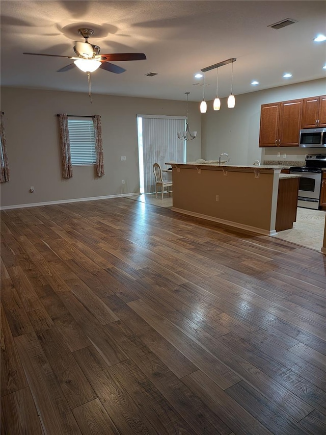 223 W Fiesta Key Loop, Deland, FL 32720 - kitchen featuring appliances with stainless steel finishes, open floor plan, dark wood-style flooring, a breakfast bar, and recessed lighting