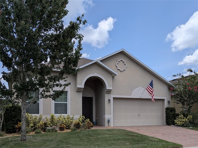 223 W Fiesta Key Loop, Deland, FL 32720 - view of front of property featuring stucco siding, decorative driveway, a garage, and a front lawn