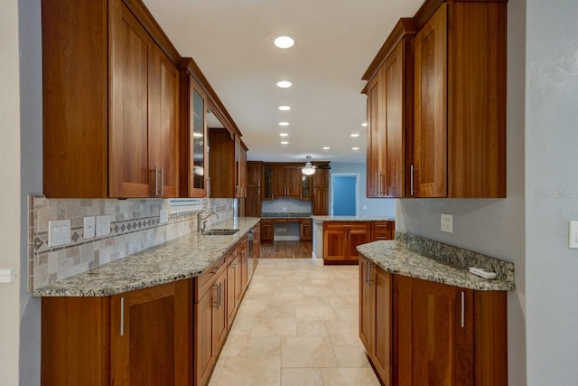 65 Sycamore Cir, Ormond Beach, FL 32174 - kitchen with brown cabinetry, a sink, recessed lighting, light stone counters, and stone finish floors