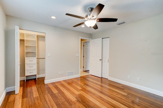 65 Sycamore Cir, Ormond Beach, FL 32174 - unfurnished bedroom featuring wood finished floors, baseboards, recessed lighting, a walk in closet, and a ceiling fan