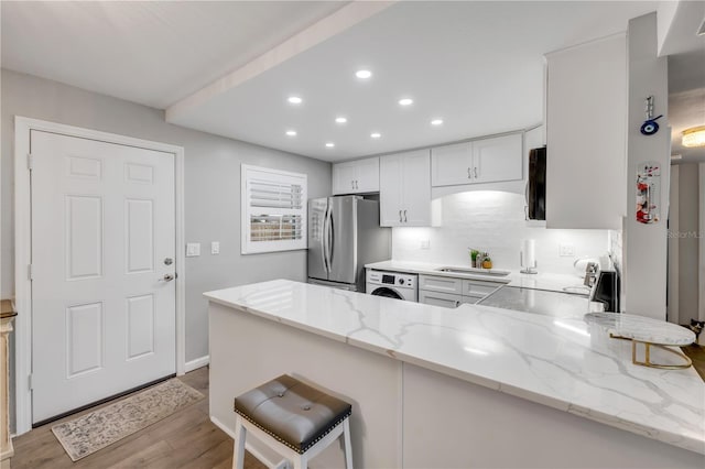 10 Lynnhurst Dr Unit 1050, Ormond Beach, FL 32176 - kitchen with freestanding refrigerator, a peninsula, light wood-type flooring, recessed lighting, and washer / dryer