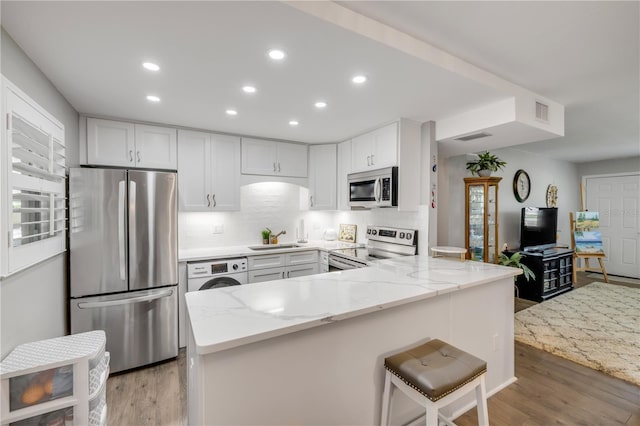10 Lynnhurst Dr Unit 1050, Ormond Beach, FL 32176 - kitchen with stainless steel appliances, light stone countertops, recessed lighting, a peninsula, and washer / clothes dryer