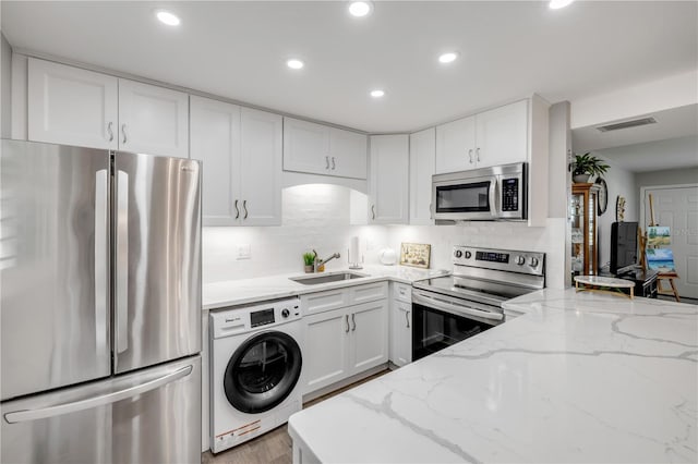 10 Lynnhurst Dr Unit 1050, Ormond Beach, FL 32176 - kitchen with appliances with stainless steel finishes, washer / clothes dryer, recessed lighting, white cabinets, and light stone countertops