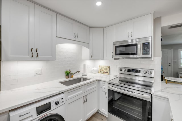 10 Lynnhurst Dr Unit 1050, Ormond Beach, FL 32176 - kitchen with stainless steel appliances, washer / clothes dryer, white cabinetry, light stone countertops, and backsplash