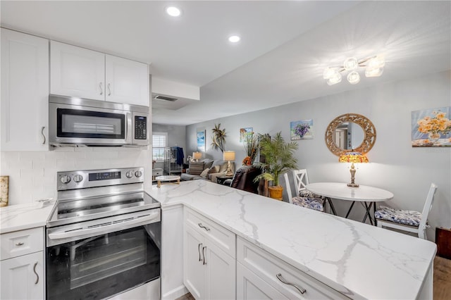 10 Lynnhurst Dr Unit 1050, Ormond Beach, FL 32176 - kitchen featuring appliances with stainless steel finishes, recessed lighting, light stone counters, white cabinets, and wood finished floors