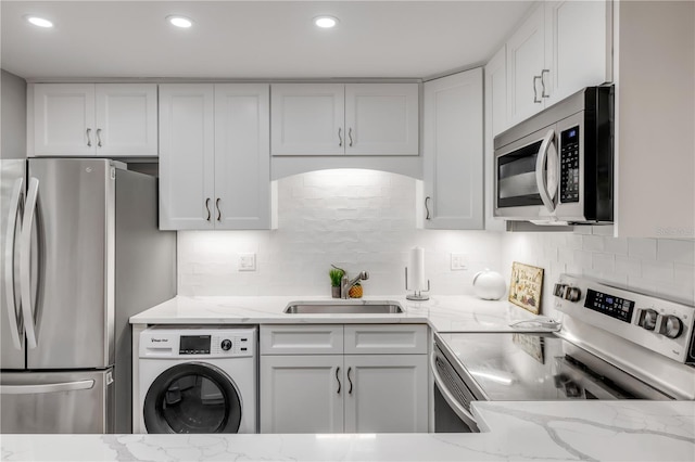 10 Lynnhurst Dr Unit 1050, Ormond Beach, FL 32176 - kitchen featuring appliances with stainless steel finishes, washer / clothes dryer, white cabinets, light stone counters, and recessed lighting