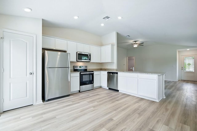 1161 Kenway Ave, Deltona, FL 32738 - kitchen with stainless steel appliances, vaulted ceiling, a peninsula, light wood-type flooring, and white cabinets