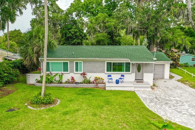 812 Faulkner St, New Smyrna Beach, FL 32168 - view of front of home featuring decorative driveway, a front lawn, a garage, roof with shingles, and stone siding