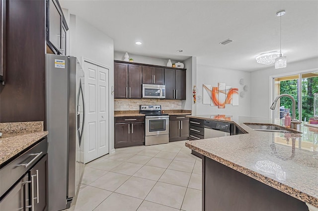 31 Abacus Ave, Ormond Beach, FL 32174 - kitchen featuring stainless steel appliances, light tile patterned floors, dark brown cabinetry, tasteful backsplash, and decorative light fixtures