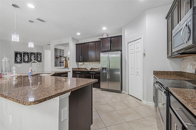 31 Abacus Ave, Ormond Beach, FL 32174 - kitchen featuring appliances with stainless steel finishes, tasteful backsplash, dark stone counters, dark brown cabinetry, and light tile patterned flooring