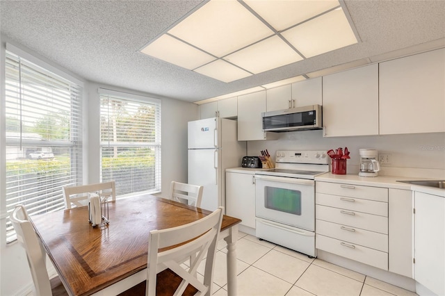 961 S Lakewood Ter Unit C, Port Orange, FL 32127 - kitchen with white appliances, light tile patterned flooring, light countertops, a textured ceiling, and white cabinets
