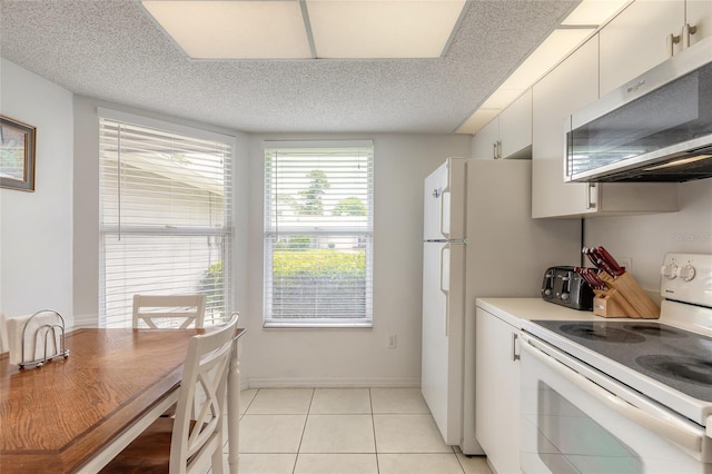 961 S Lakewood Ter Unit C, Port Orange, FL 32127 - kitchen with electric range, stainless steel microwave, light tile patterned flooring, white cabinetry, and light countertops