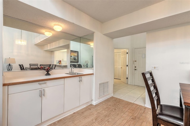 961 S Lakewood Ter Unit C, Port Orange, FL 32127 - kitchen featuring light countertops, light wood-style flooring, white cabinets, and a chandelier