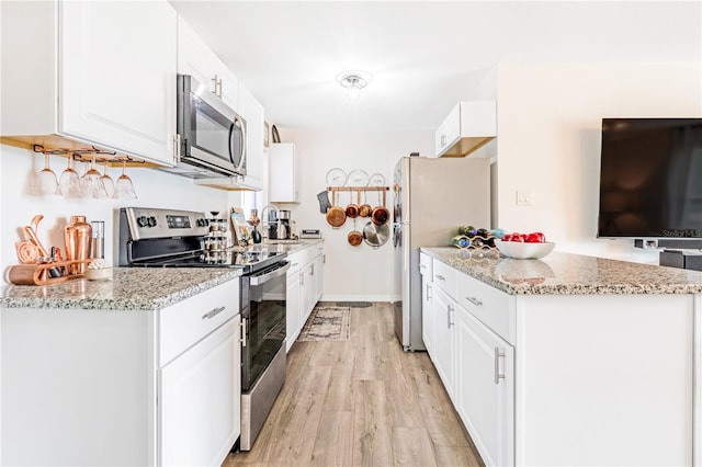 1455 Whitewood Dr, Deltona, FL 32725 - kitchen with appliances with stainless steel finishes, light wood-type flooring, white cabinets, light stone countertops, and a peninsula
