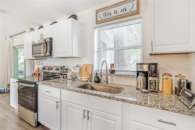 1455 Whitewood Dr, Deltona, FL 32725 - kitchen featuring stainless steel appliances, white cabinetry, light stone counters, and light wood-style floors