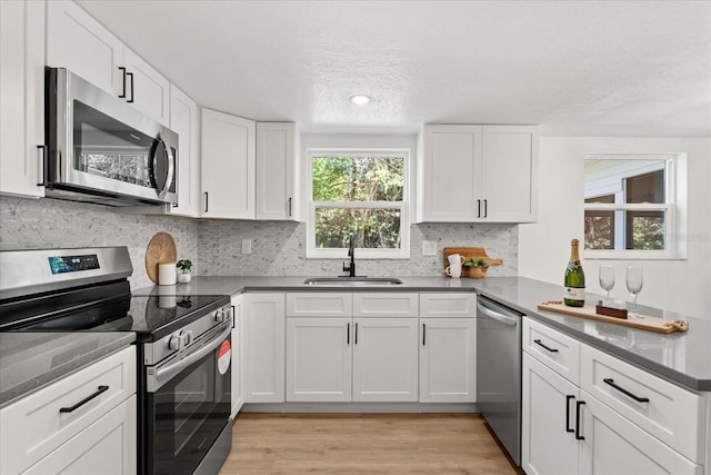 3655 Scott St, Port Orange, FL 32129 - kitchen featuring stainless steel appliances, white cabinetry, light wood-type flooring, decorative backsplash, and a textured ceiling