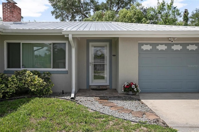 502 W Hogle Ave, Deland, FL 32720 - view of exterior entry with stucco siding, a garage, a metal roof, and concrete driveway