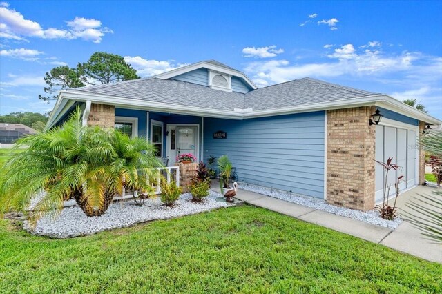 123 Wood Ibis Ct, Daytona Beach, FL 32119 - single story home featuring brick siding, roof with shingles, a front yard, a porch, and an attached garage