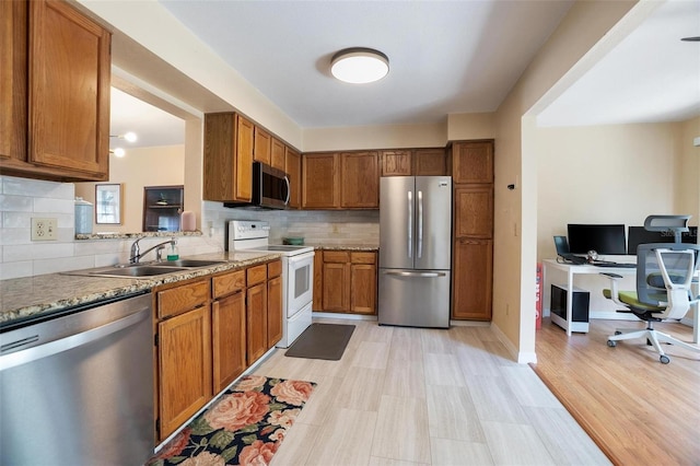 874 Commonwealth Ct, Casselberry, FL 32707 - kitchen featuring appliances with stainless steel finishes, brown cabinetry, a desk, and tasteful backsplash