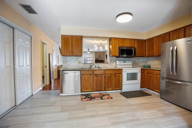 874 Commonwealth Ct, Casselberry, FL 32707 - kitchen with appliances with stainless steel finishes, brown cabinets, decorative backsplash, and light stone counters