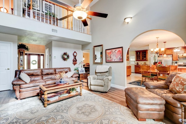 1383 Tumblin Dr, New Smyrna Beach, FL 32168 - living room featuring arched walkways, a chandelier, a towering ceiling, light wood-style flooring, and a ceiling fan