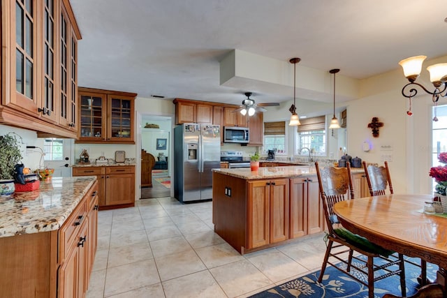 1383 Tumblin Dr, New Smyrna Beach, FL 32168 - kitchen featuring appliances with stainless steel finishes, brown cabinets, a peninsula, ceiling fan, and light stone countertops