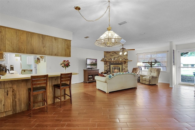270 Sandyhook Ln, Deland, FL 32724 - living room featuring a textured ceiling, a chandelier, wood finished floors, ceiling fan, and a fireplace