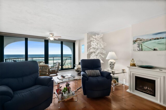 3003 S Atlantic Ave Unit 3A2, Daytona Beach Shores, FL 32118 - living room with a wall of windows, wood finished floors, ceiling fan, a water view, and a lit fireplace
