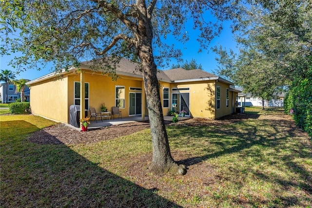 727 Grape Ivy Ln, New Smyrna Beach, FL 32168 - back of house featuring stucco siding, a yard, and a patio